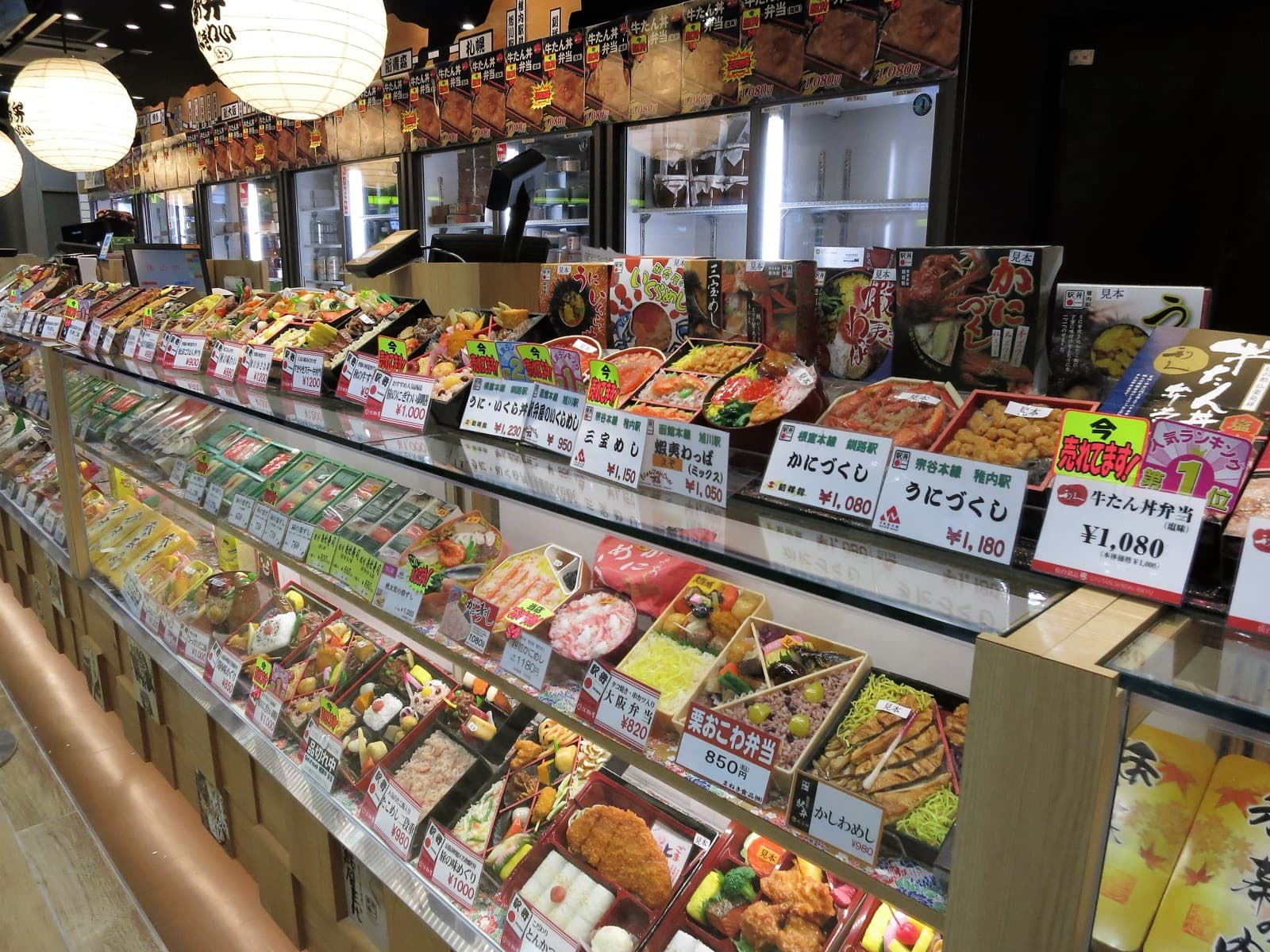 A display of colorful shinkansen ekiben lunch boxes for sale at a station in Japan.