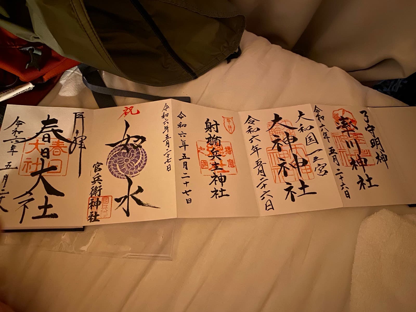 Libro goshuin abierto con varios sellos rojos de templos y santuarios japoneses.