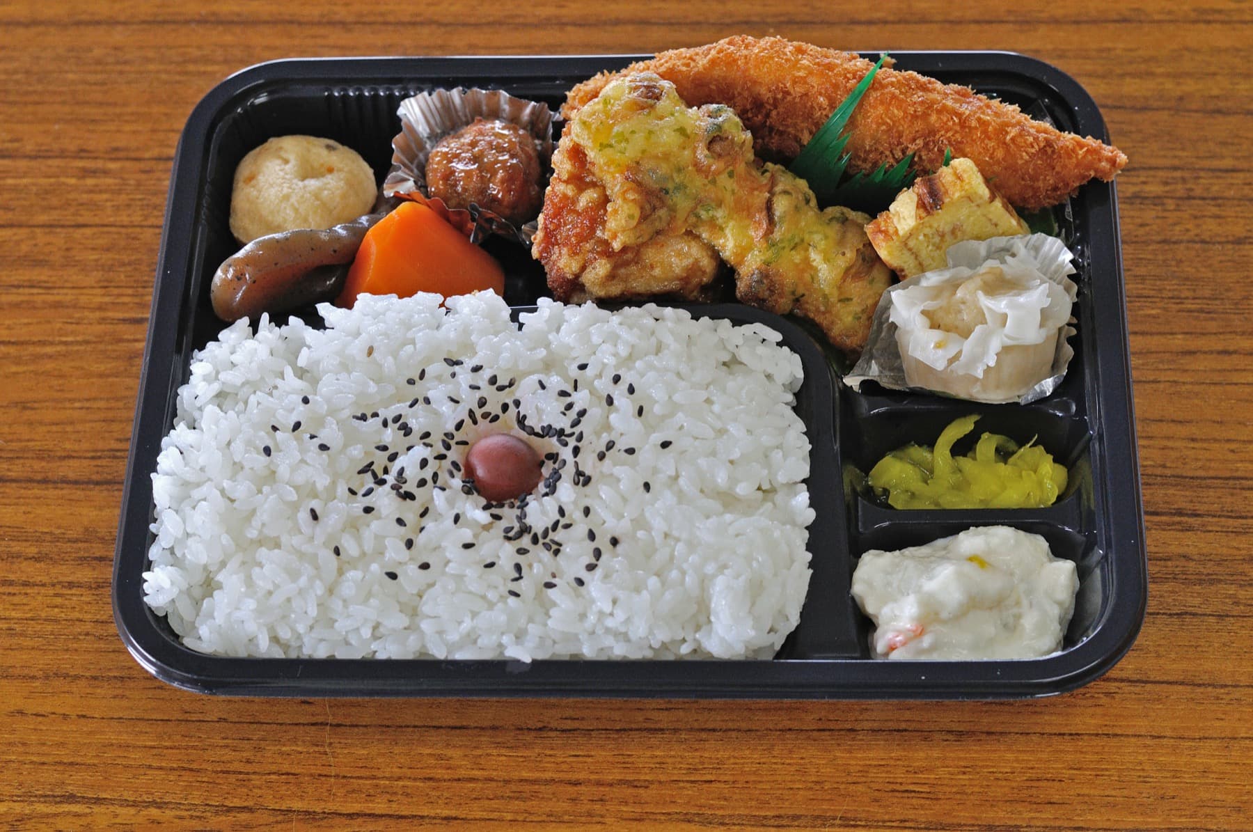 Comida bento japonesa tradicional organizada dentro de una caja compartimentada.