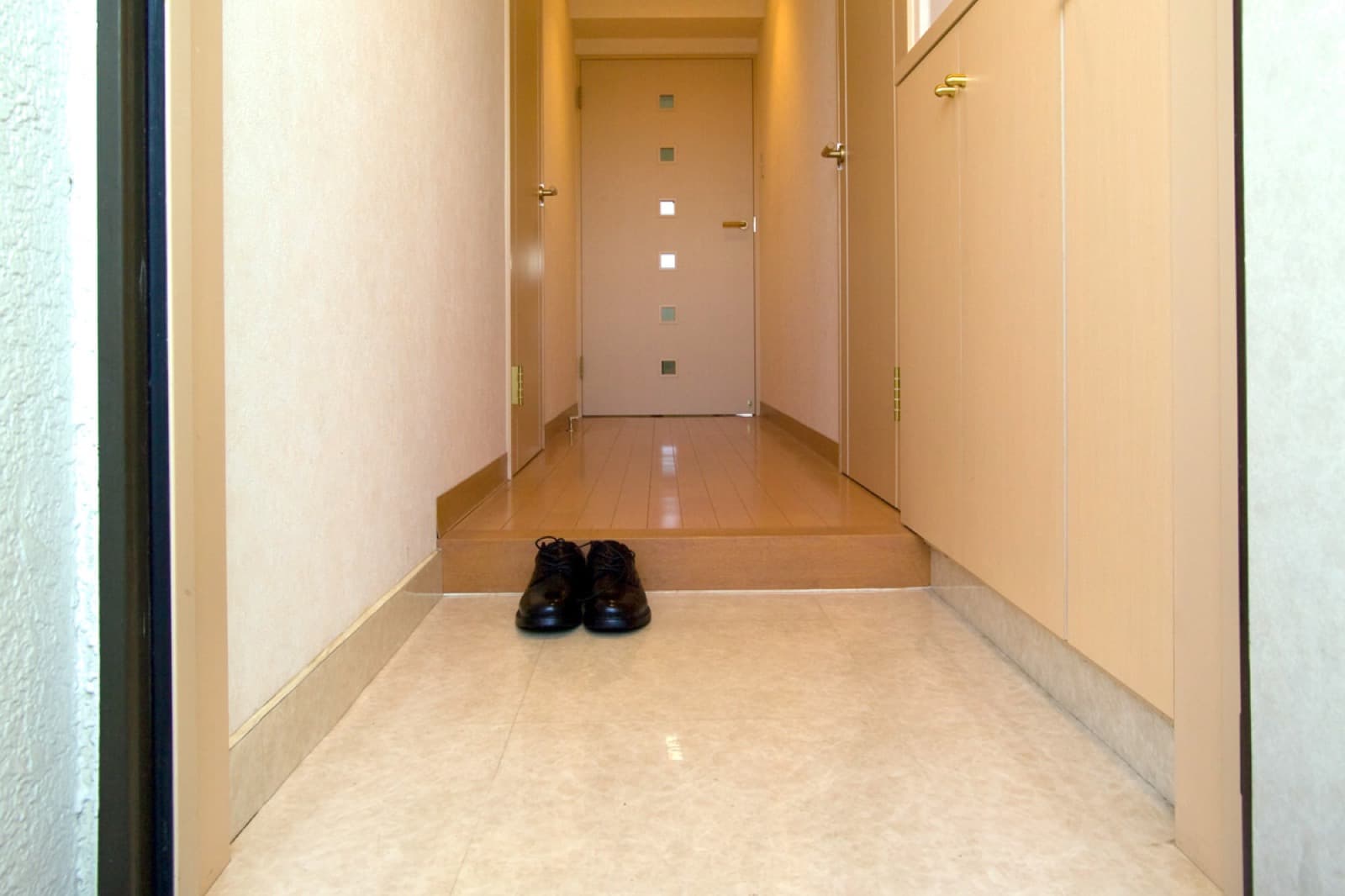 Entrada tradicional japonesa tipo genkan con zapatos colocados sobre el suelo de baldosas.