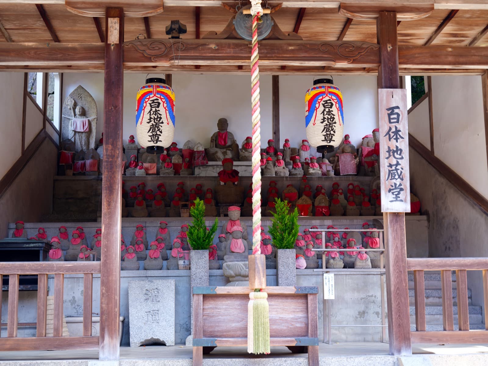 A row of stone Jizo statues in old Kyoto, each dressed with red bibs and cloth details.
