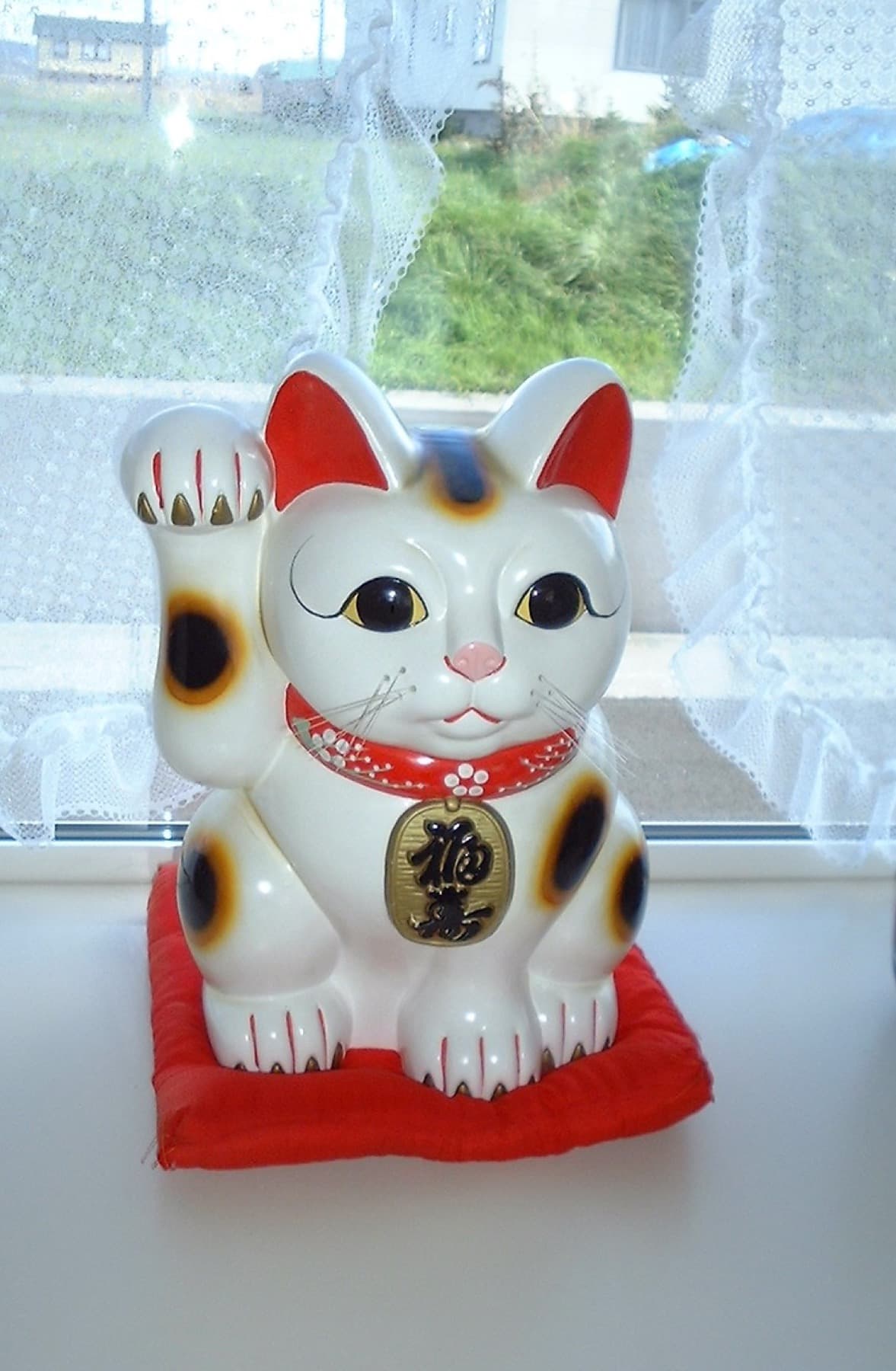 A traditional white maneki-neko lucky cat statue displayed indoors in Hokkaido, Japan.