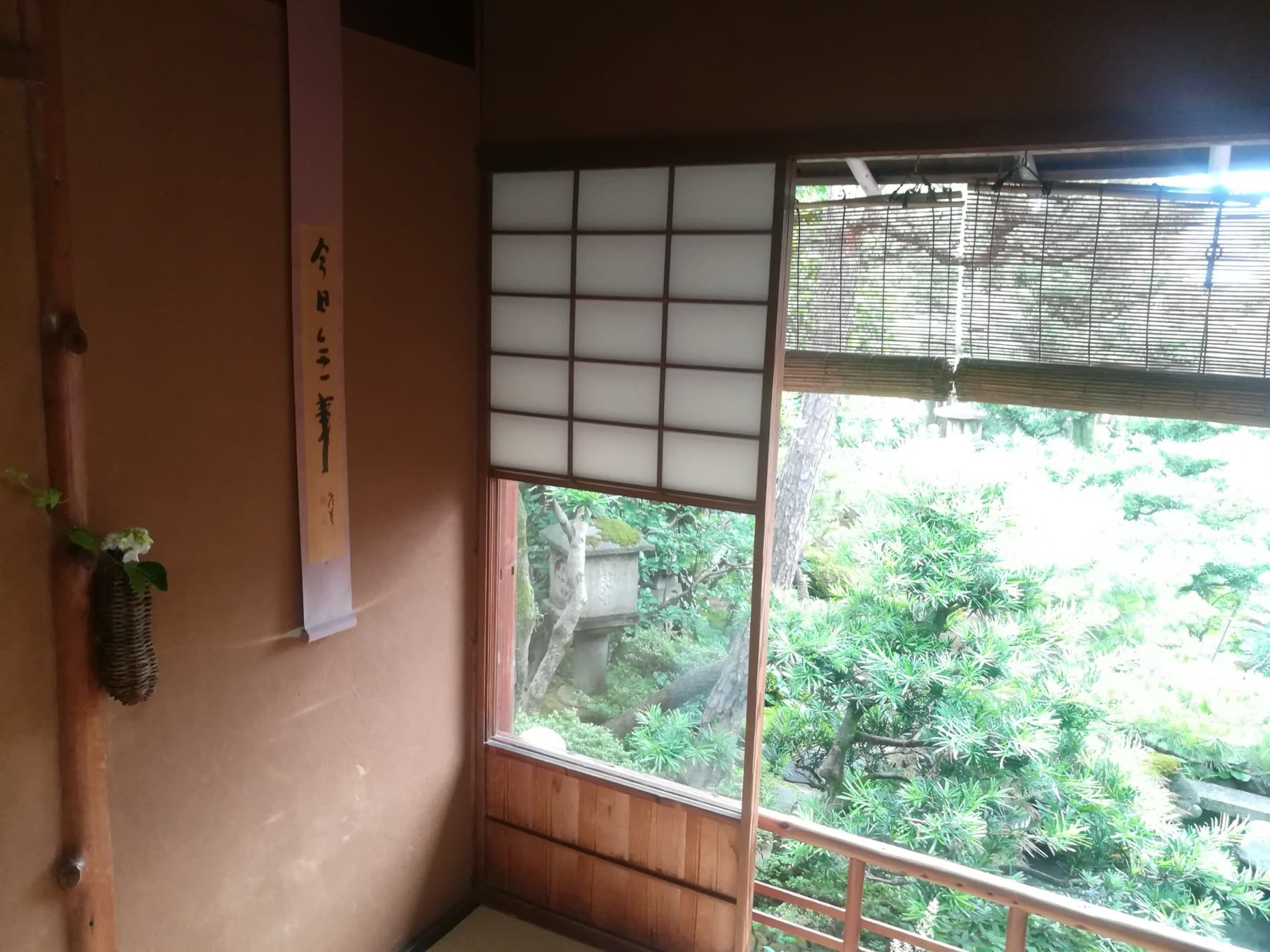 A traditional Japanese tokonoma alcove with hanging scroll and a view toward a garden.