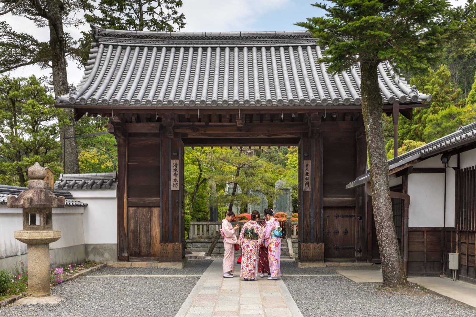 Women wearing yukata in front of a temple gate in Kyoto, Japan.